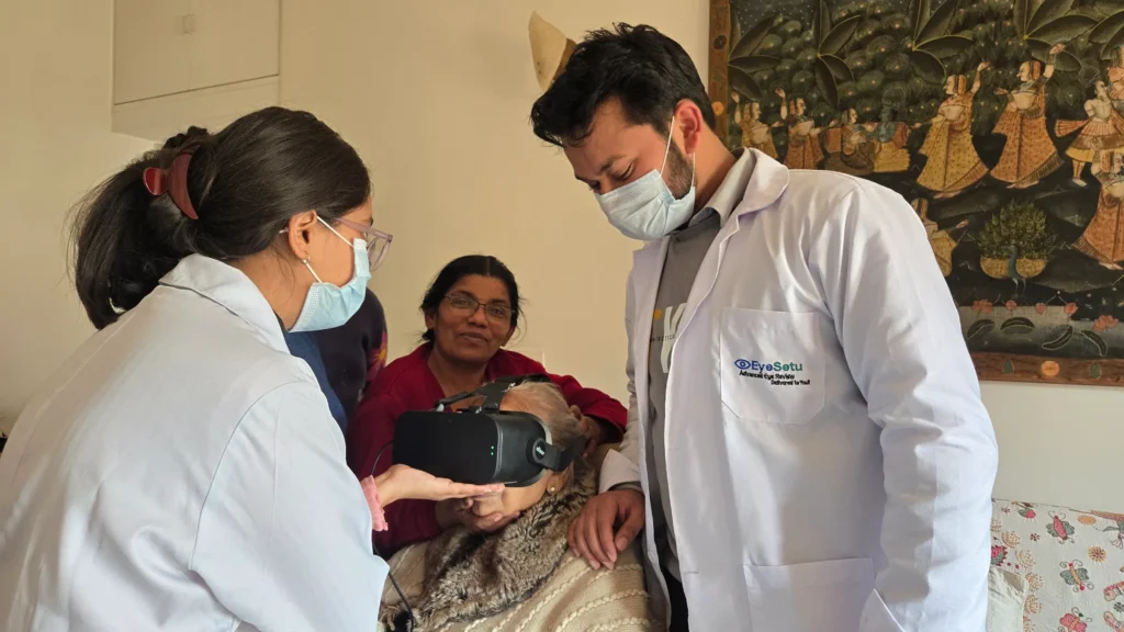 Two EyeSetu optometrists testing an elderly woman with a visual field headset at home, her daughter beside her