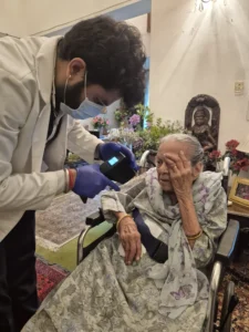 Doctor examining an elderly woman in a wheelchair at home