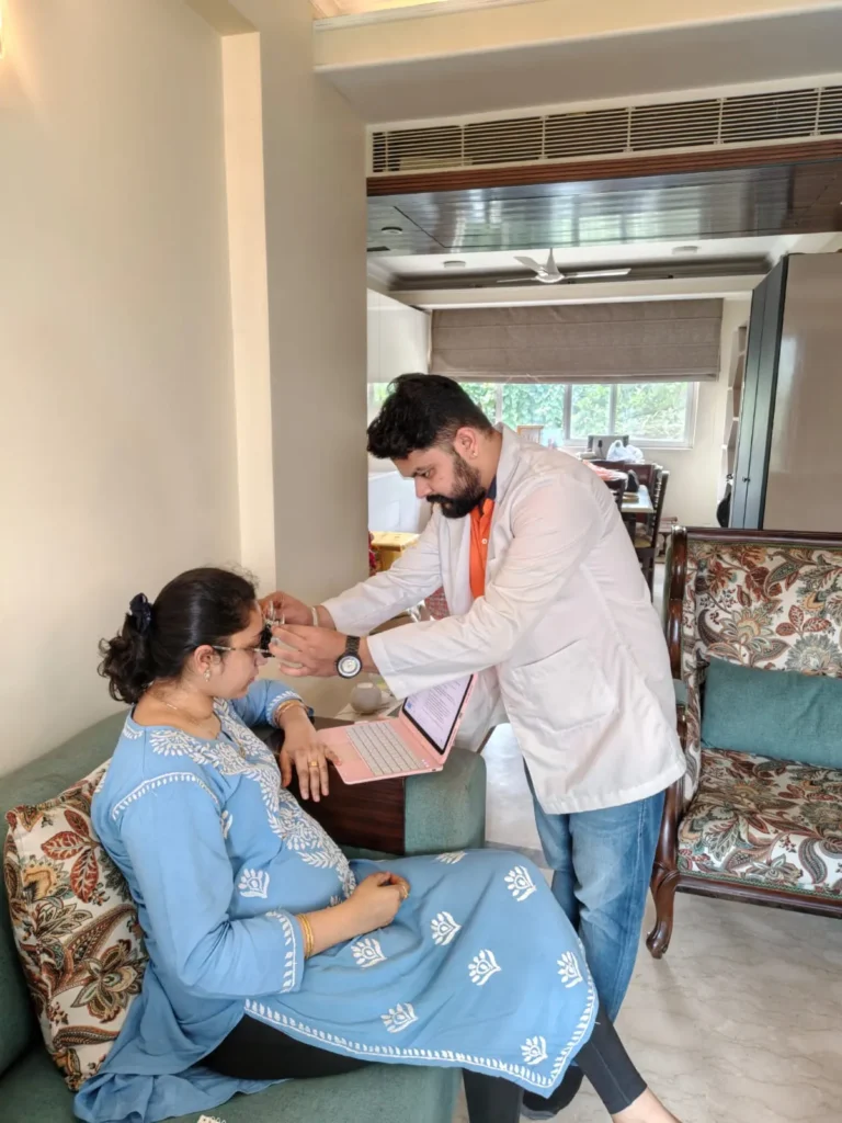 Doctor examining a woman seated on her sofa at home